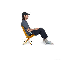 Lightweight folding camping chair with orange frame and black seat, person sitting outdoors