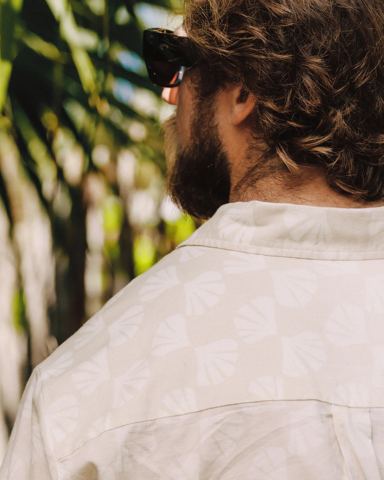 Light colored short sleeve button-up shirt worn by man outdoors, back view
