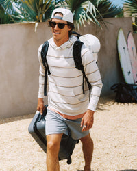 Man wearing a striped lightweight pullover hoodie with backpack and luggage outdoors
