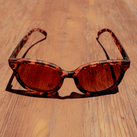 Tortoiseshell cat-eye sunglasses with brown tinted lenses, front view on wooden surface