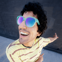 Person wearing oversized mint green frame sunglasses with purple mirrored lenses, smiling outdoors