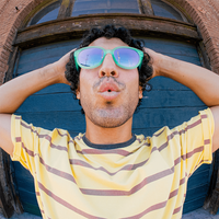 Person wearing oversized wayfarer-style sunglasses with mint green frames and blue mirrored lenses