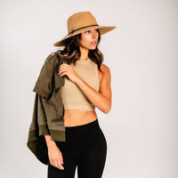 Wide brim straw sun hat with dark cord band, worn by model in lifestyle setting