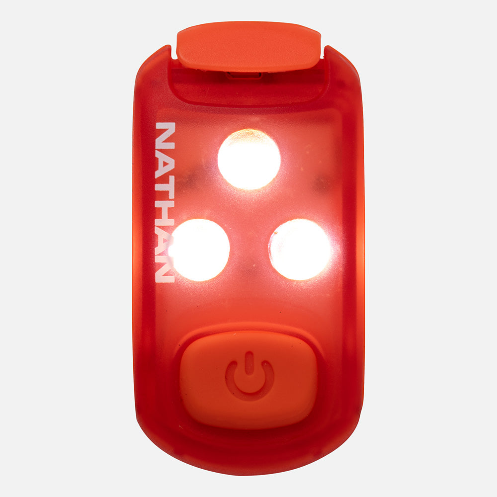 Red LED safety light clip with three bright white lights illuminated and power button visible