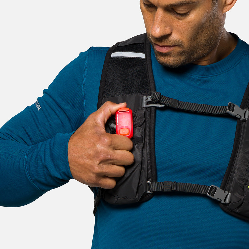 Red LED safety light clipped to black vest strap, compact rectangular design