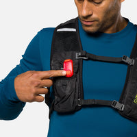 Red LED safety light clipped to black chest harness worn by person in blue shirt