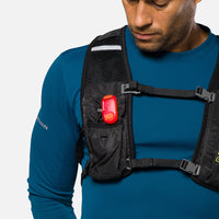 Red LED safety light clipped to black running vest strap on runner's chest
