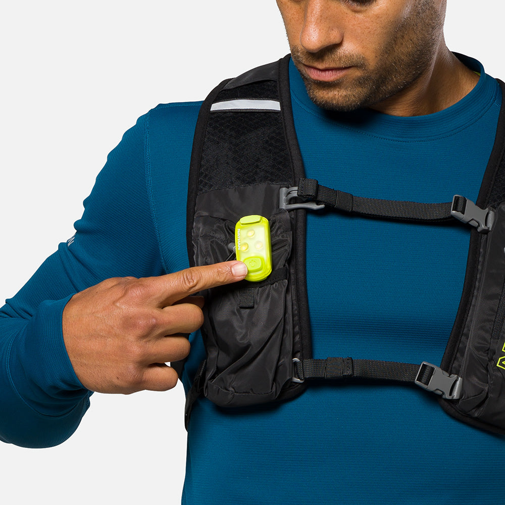 Bright LED safety light clipped to black chest pack worn by person in blue shirt