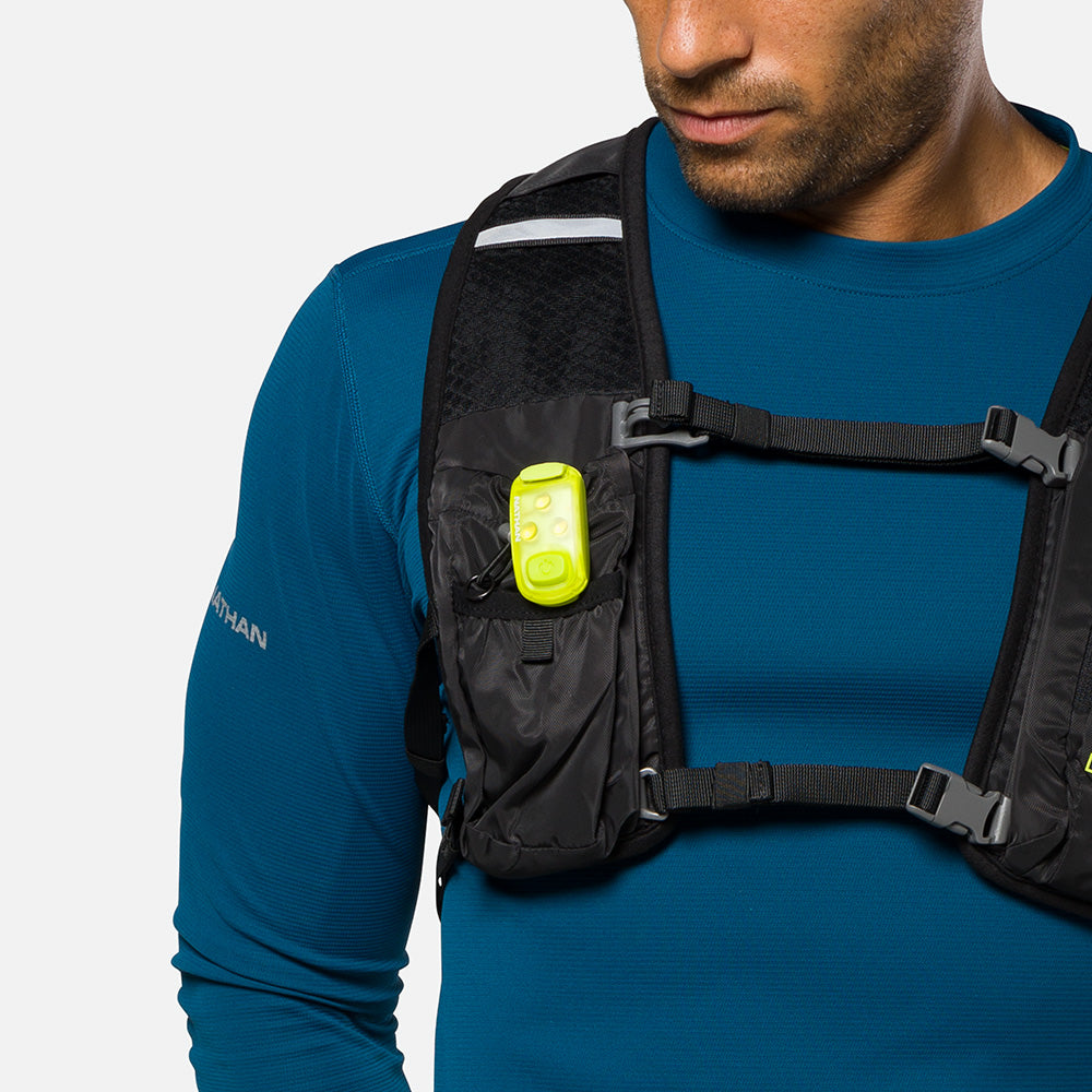 Bright yellow LED safety light clipped to black running vest chest strap