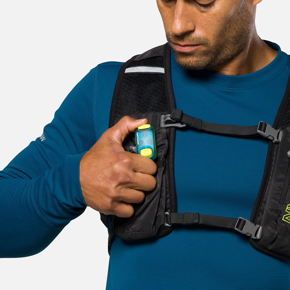 LED safety light clipped to black chest harness worn over blue athletic shirt