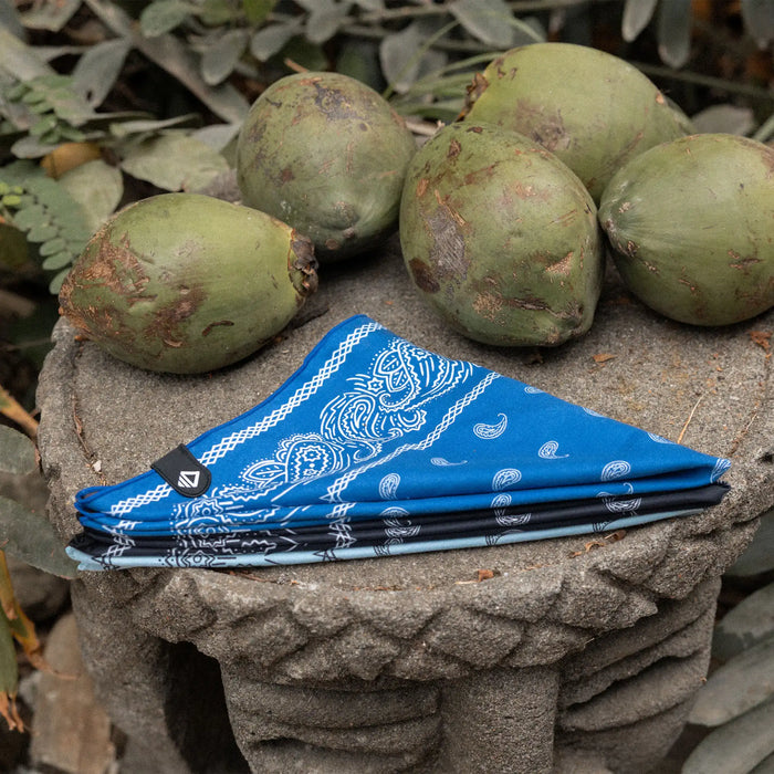 Blue bandana towel with white paisley pattern folded on stone surface with coconuts