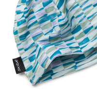 Close-up detail of a patterned beanie hat showing label and abstract brushstroke print