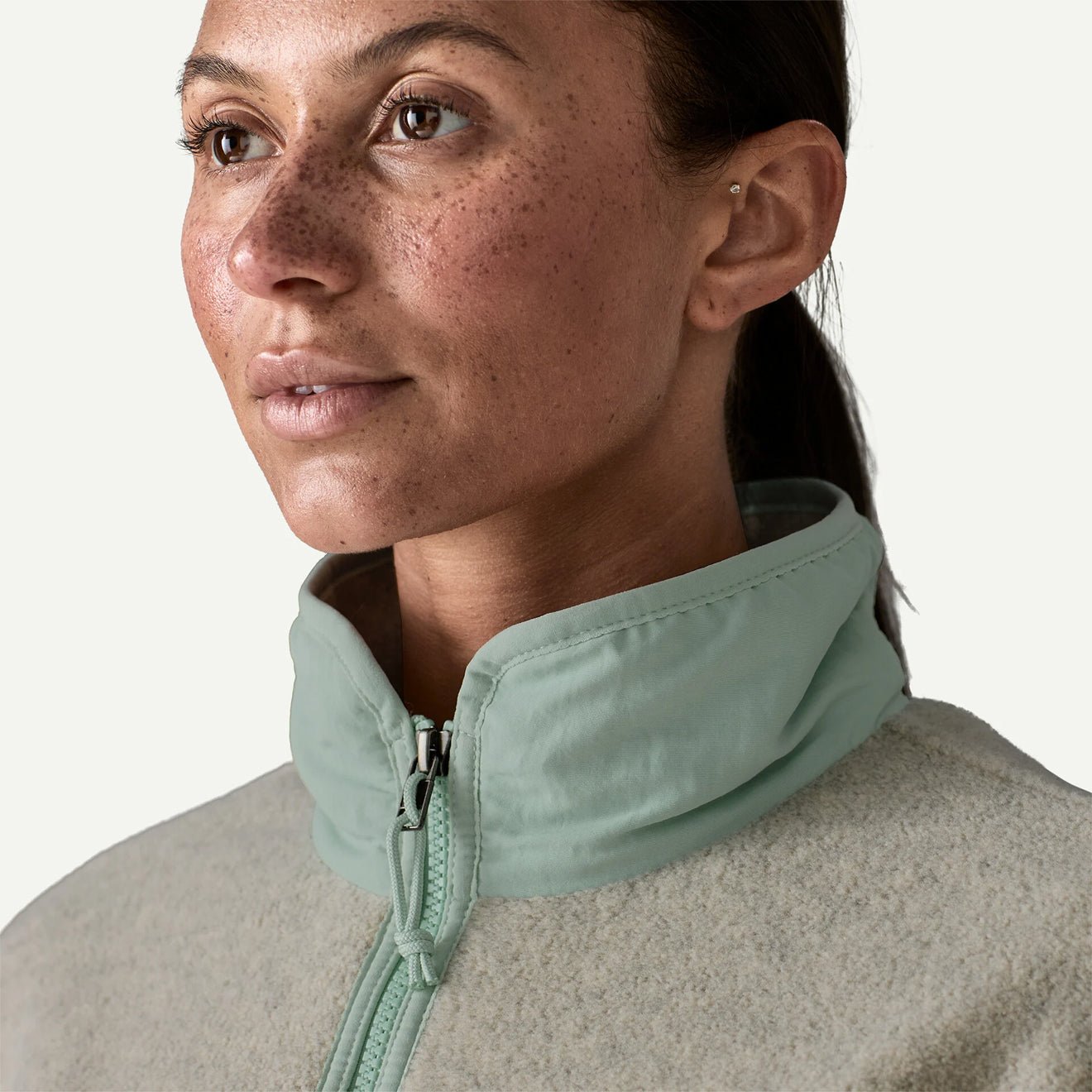 Close-up detail of women's fleece jacket collar with mint green zip and stand collar