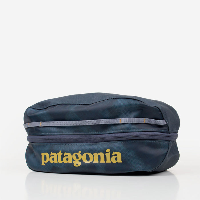 Dark blue travel cube bag with zipper closure, grab handle, and yellow brand logo, front view