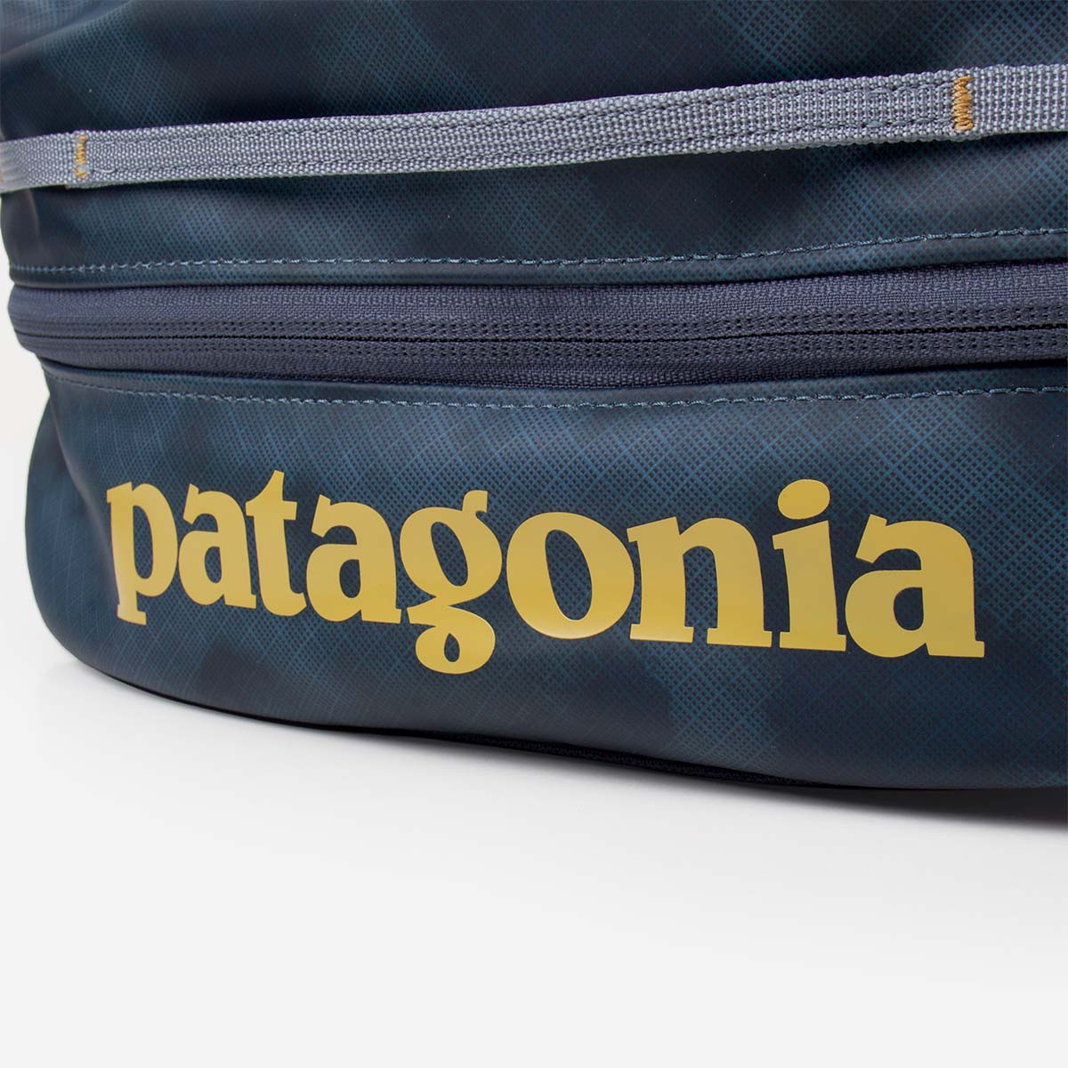 Close-up detail of a dark blue cube packing organizer with gold brand lettering and zipper