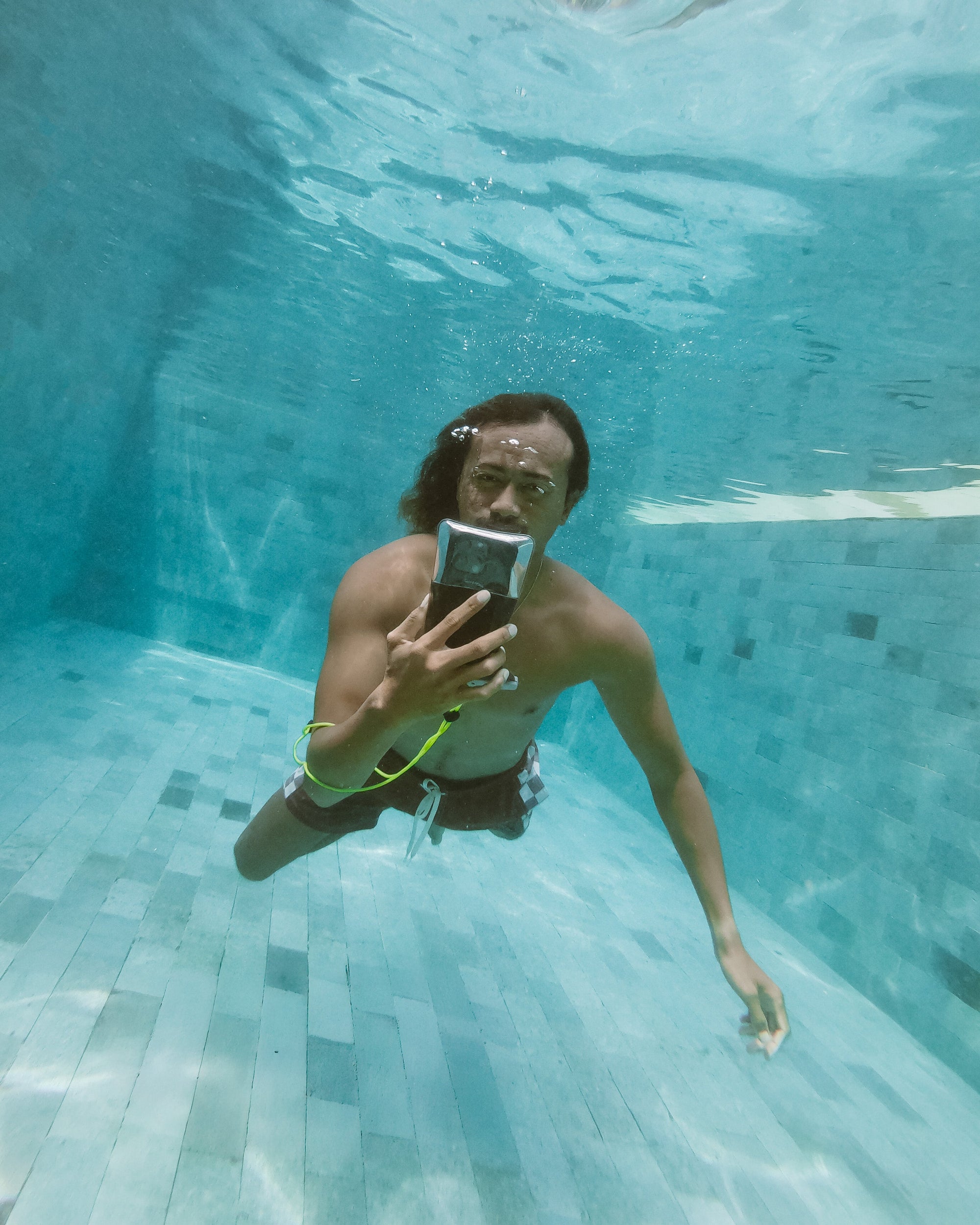 Waterproof phone case being used underwater in swimming pool, clear case with black accents
