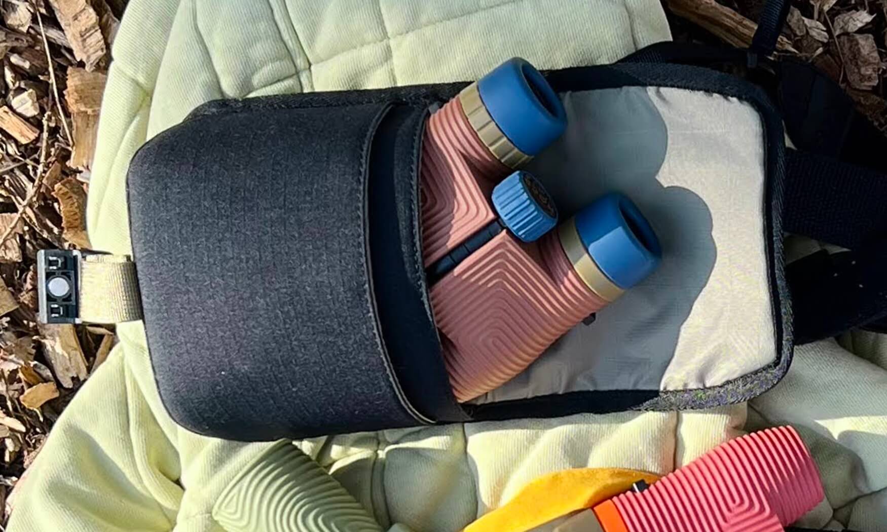 Open binocular field pouch in dark charcoal with light interior, shown with binoculars inside
