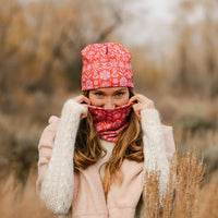 Woman wearing a red and pink floral neck gaiter pulled up over nose, outdoors