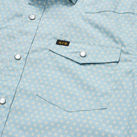 Close-up detail of light blue floral snap shirt showing chest pocket and pearl snap buttons