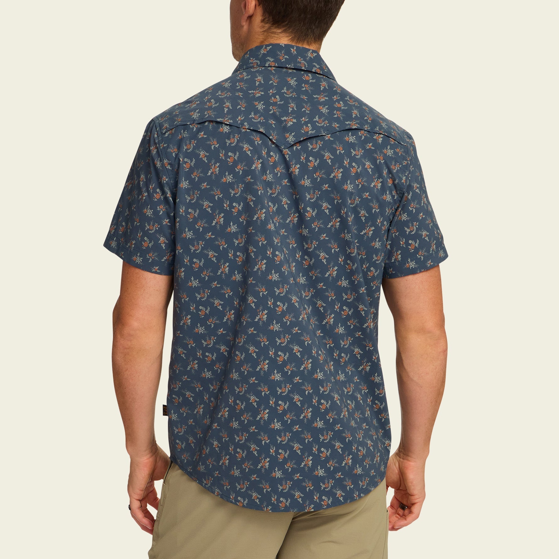 Dark blue short-sleeve button-up shirt with small floral pattern, back view on model
