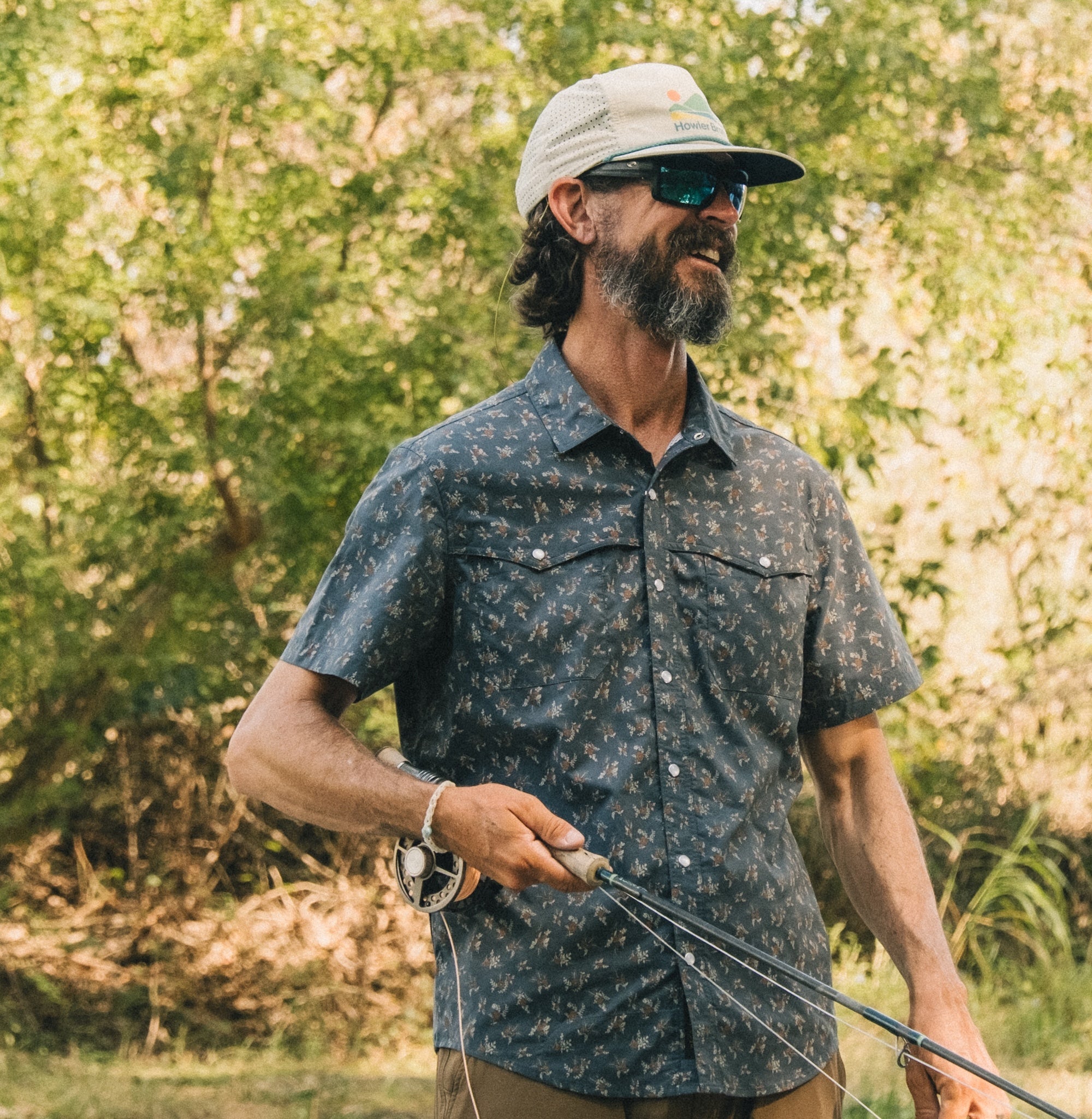 Man wearing dark floral print button-up shirt with chest pockets in outdoor setting