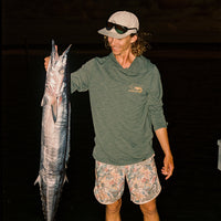 Man wearing olive green long-sleeve hoodie holding fish, lifestyle shot