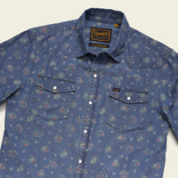 Men's floral print western snap shirt in washed indigo denim, angled front view showing dual chest pockets