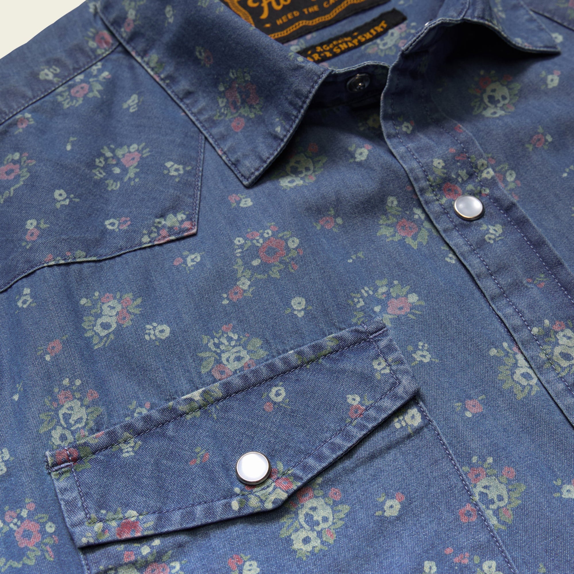 Close-up detail of floral print western snap shirt with chest pocket and silver snap buttons