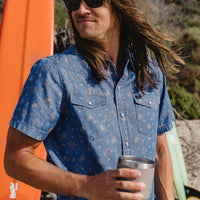 Men's short-sleeve snap-button denim shirt with floral print, worn on model outdoors