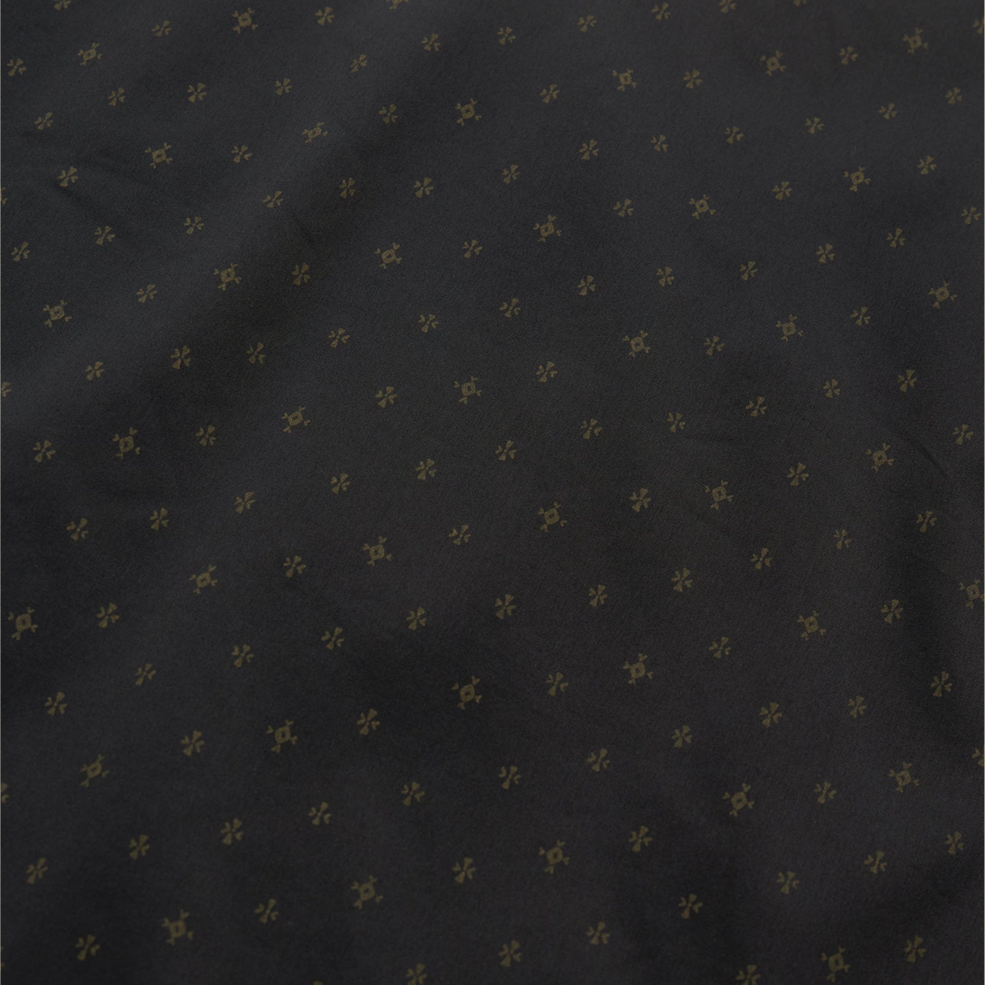Dark shirt fabric with small golden star pattern scattered across surface