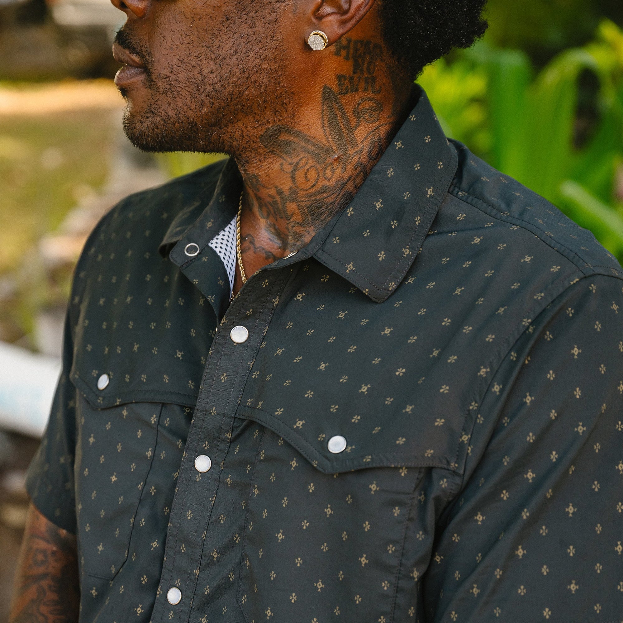 Dark western-style shirt with small gold star pattern and pearl snap buttons, worn outdoors