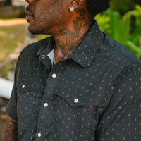 Dark western-style shirt with small gold star pattern and pearl snap buttons, worn outdoors