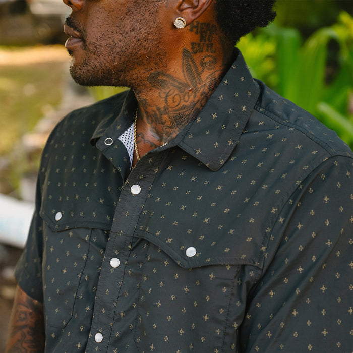 Dark western-style shirt with small gold star pattern and pearl snap buttons, worn outdoors