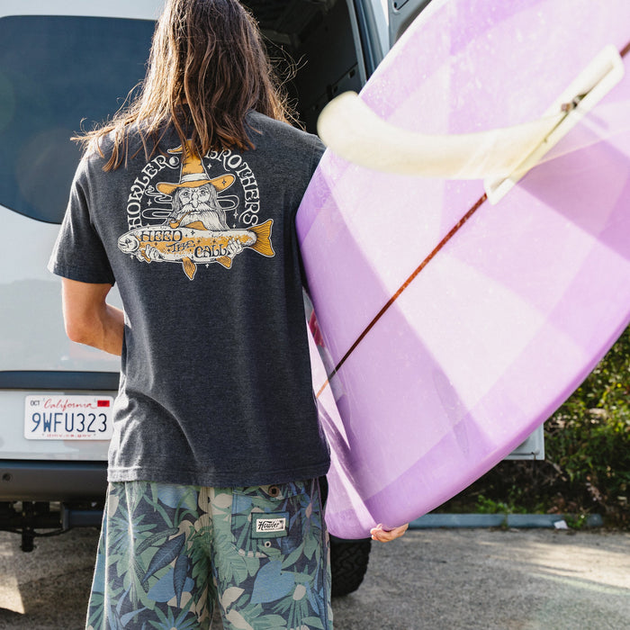 Dark heather t-shirt with fishing-themed graphic on back, worn by person carrying surfboard