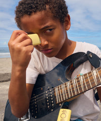 Yellow sunscreen face stick being applied to child's nose at beach