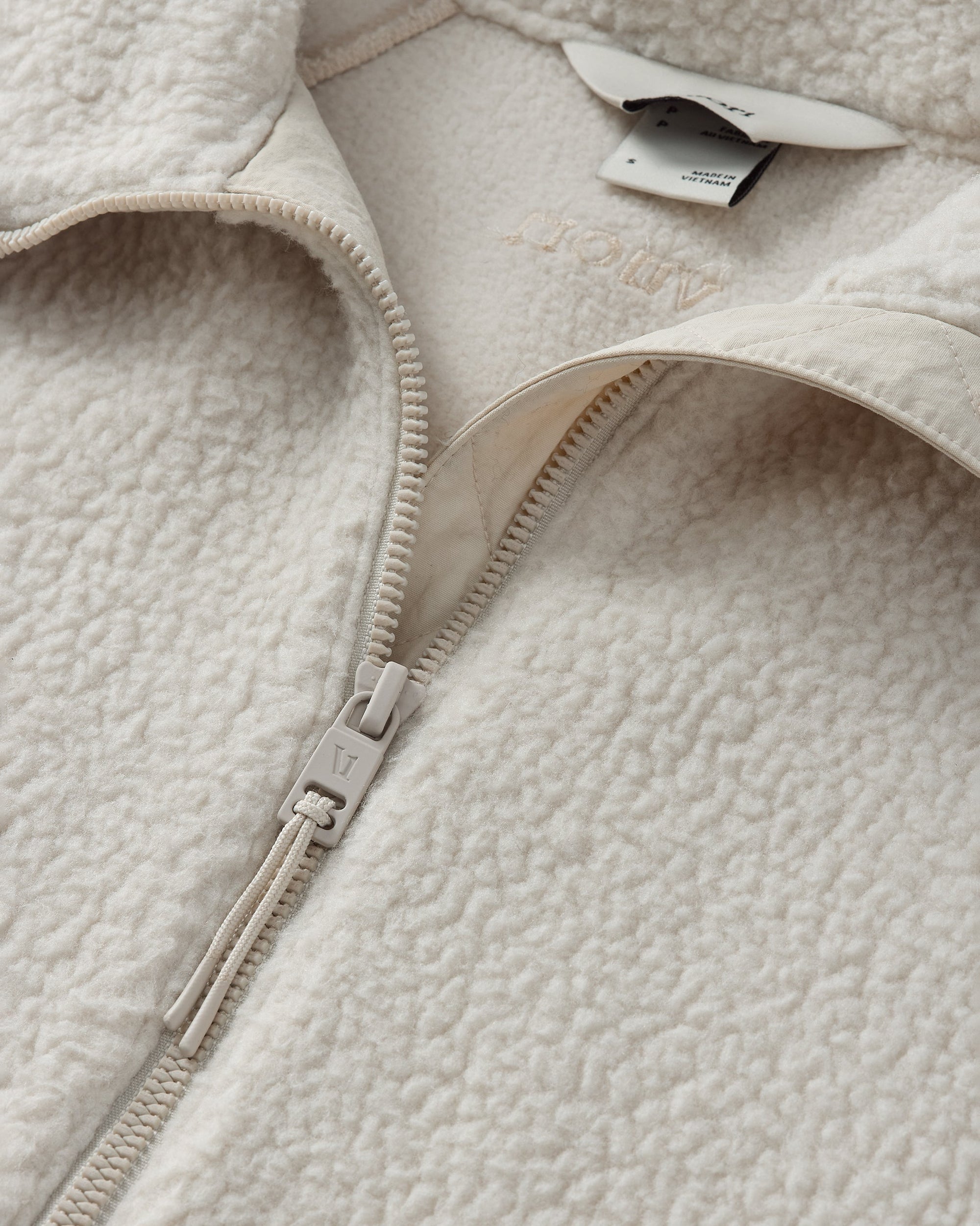 Close-up detail of a sherpa fleece jacket showing zipper, collar, and texture