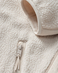 Close-up detail of sherpa fleece jacket showing zipper pull, collar, and textured fabric