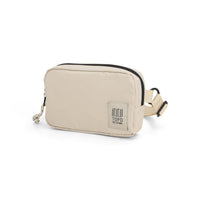 Cream colored belt bag with black zipper trim and adjustable strap, quarter view