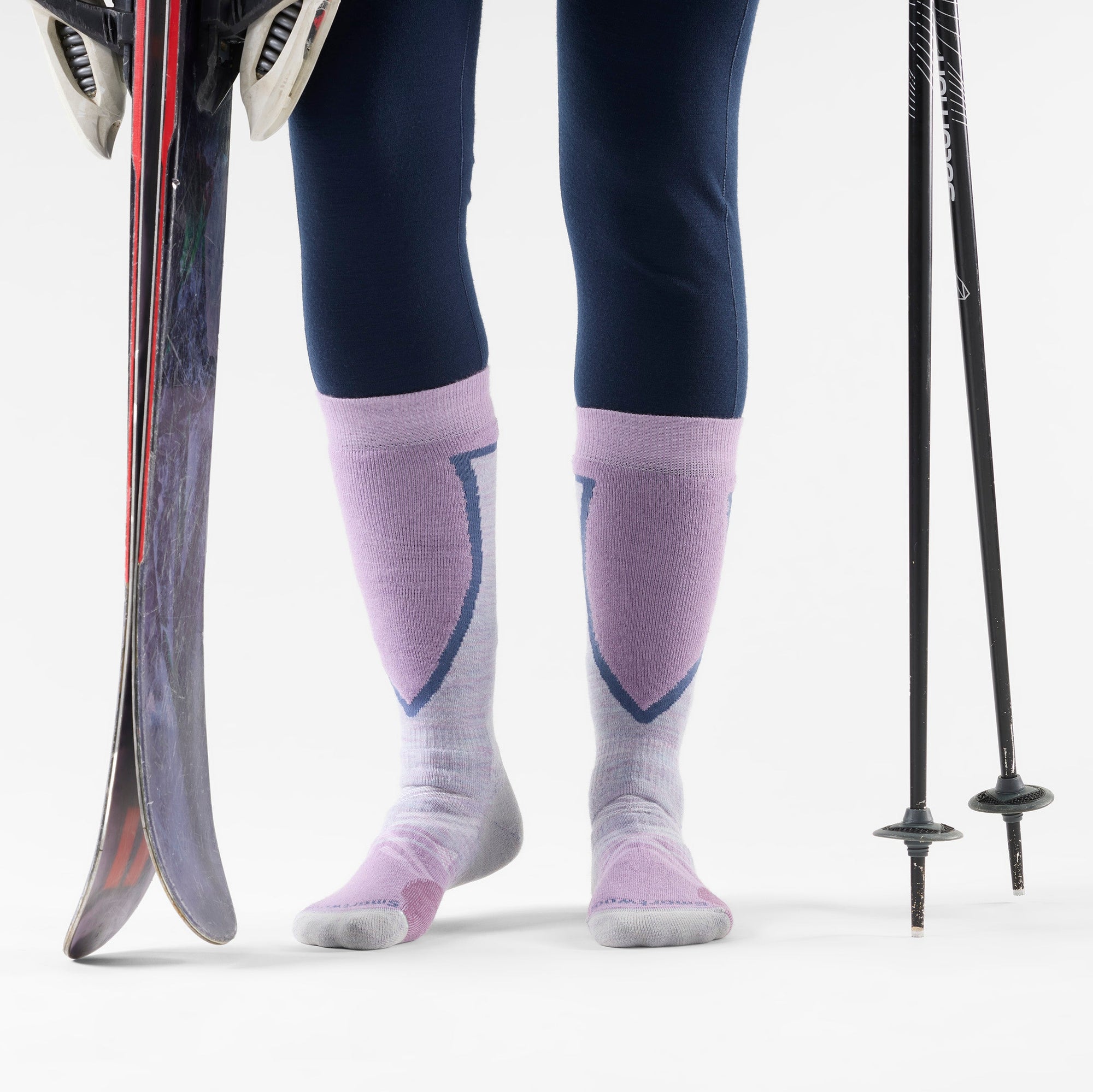 Over-the-calf ski socks in lavender with purple and navy cushioned panels, on-model with skis
