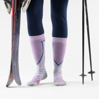 Over-the-calf ski socks in lavender with purple and navy cushioned panels, on-model with skis