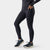 Women's black full-length athletic tights with side pocket, shown from side angle with running shoes