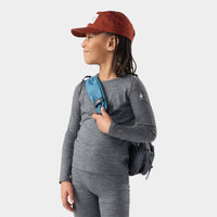 Child wearing long-sleeve gray heather base layer crew with small backpack and red cap