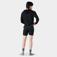 Back view of model wearing black fitted boxer brief shorts with branded waistband and striped socks