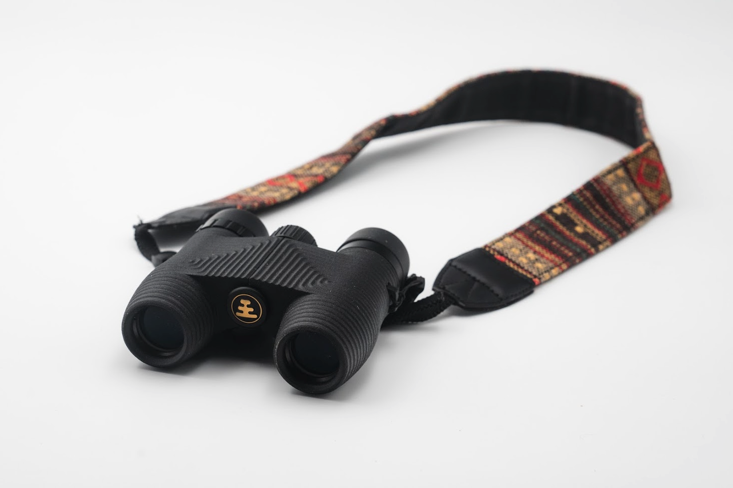 Compact black binoculars with multicolor woven tapestry neck strap featuring ethnic geometric pattern