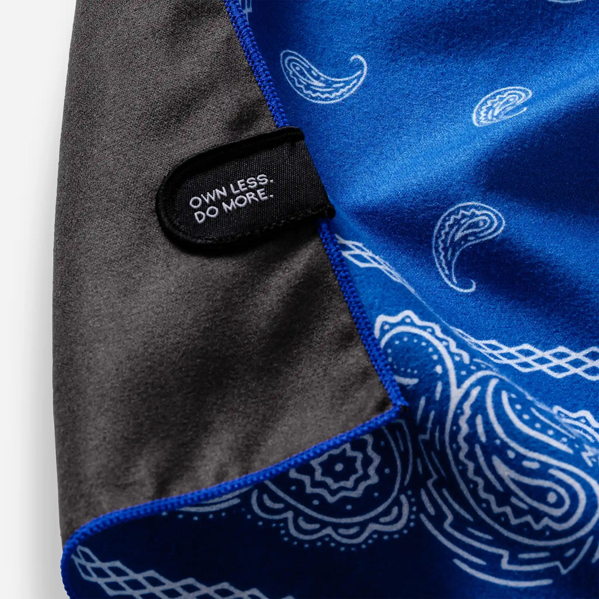 Blue bandana towel with white paisley pattern and black label detail