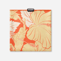 Square towel with orange and cream hibiscus flower pattern, flat lay view