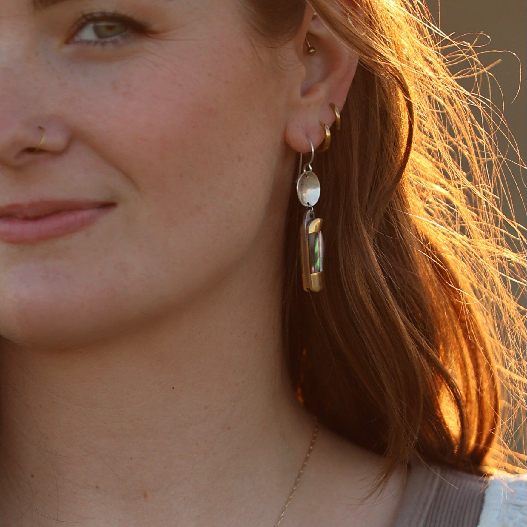 Dangle earring with silver circle top and rectangular abalone shell pendant, worn on model