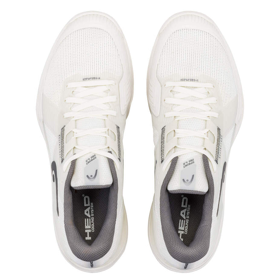 Top-down view of a pair of white tennis shoes with grey insoles and laces