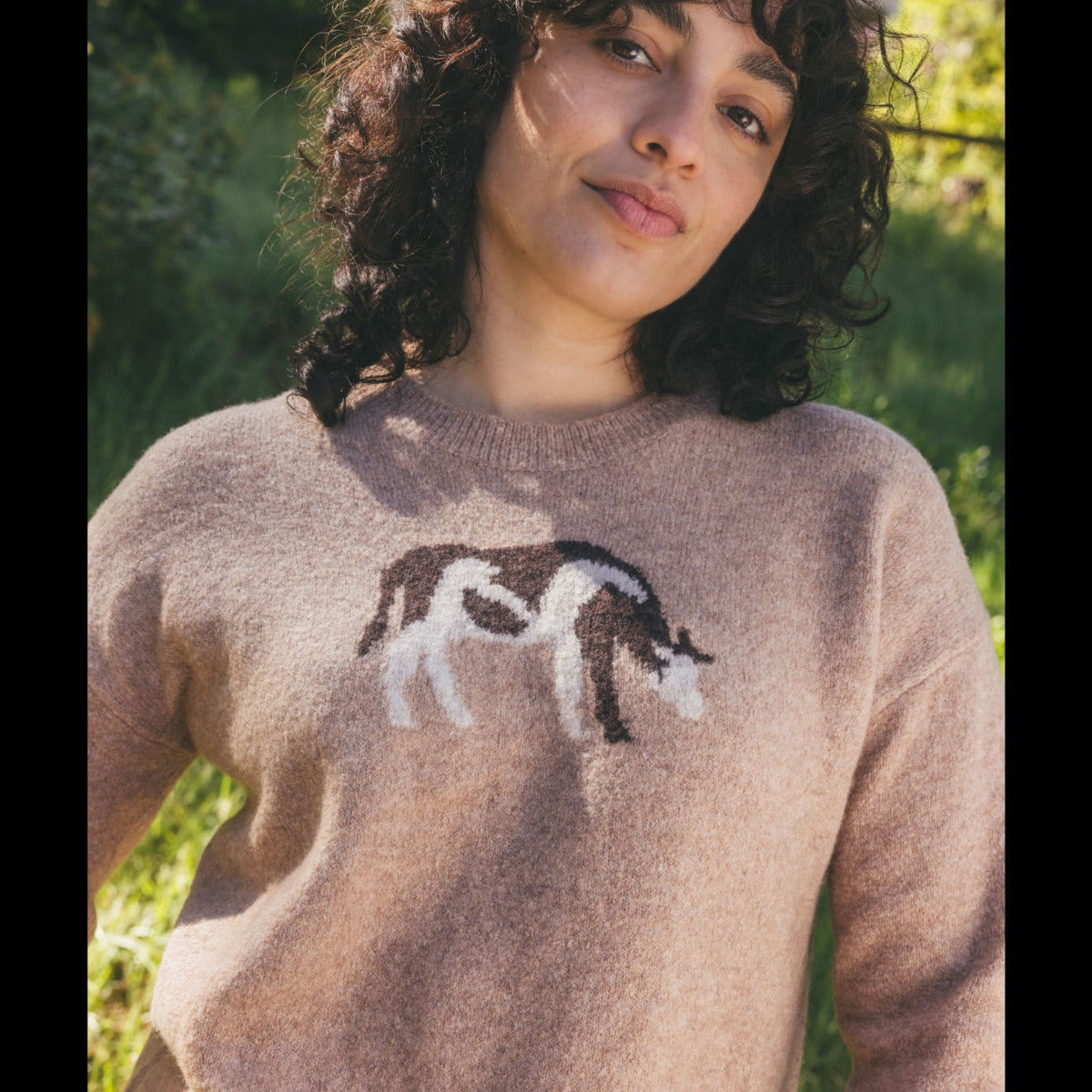 Women's crew neck knit sweater in beige with brown and white horse intarsia pattern, on-model lifestyle shot