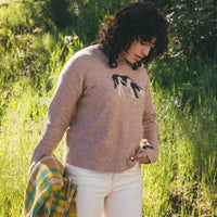 Women's crew neck knit sweater in tan with black and white animal jacquard pattern, outdoor lifestyle shot